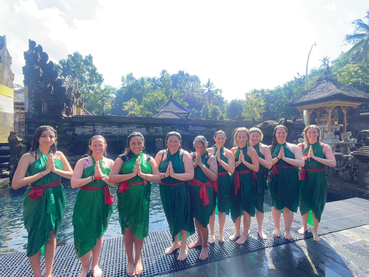 Women participating in a traditional Balinese water purification ceremony during a wellness retreat activity in Bali